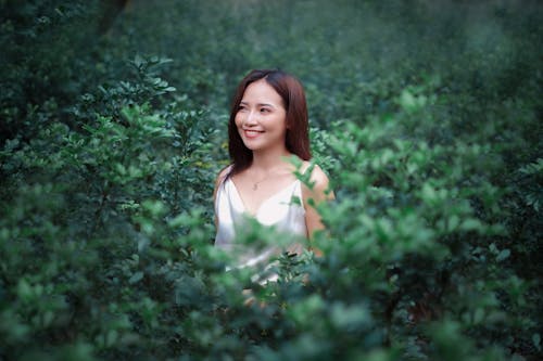 Smiling Woman Standing Between Shrubs 