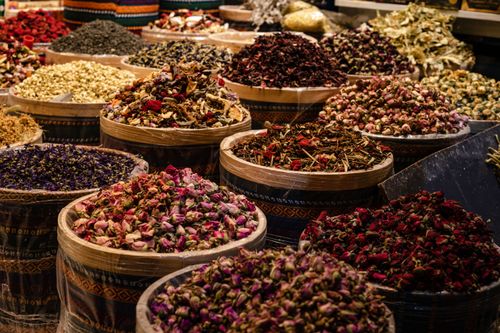 Free A colorful display of dried spices and herbs in barrels at a bustling market. Stock Photo