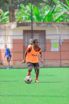 A young boy dribbling a soccer ball during practice on a sunny outdoor field.