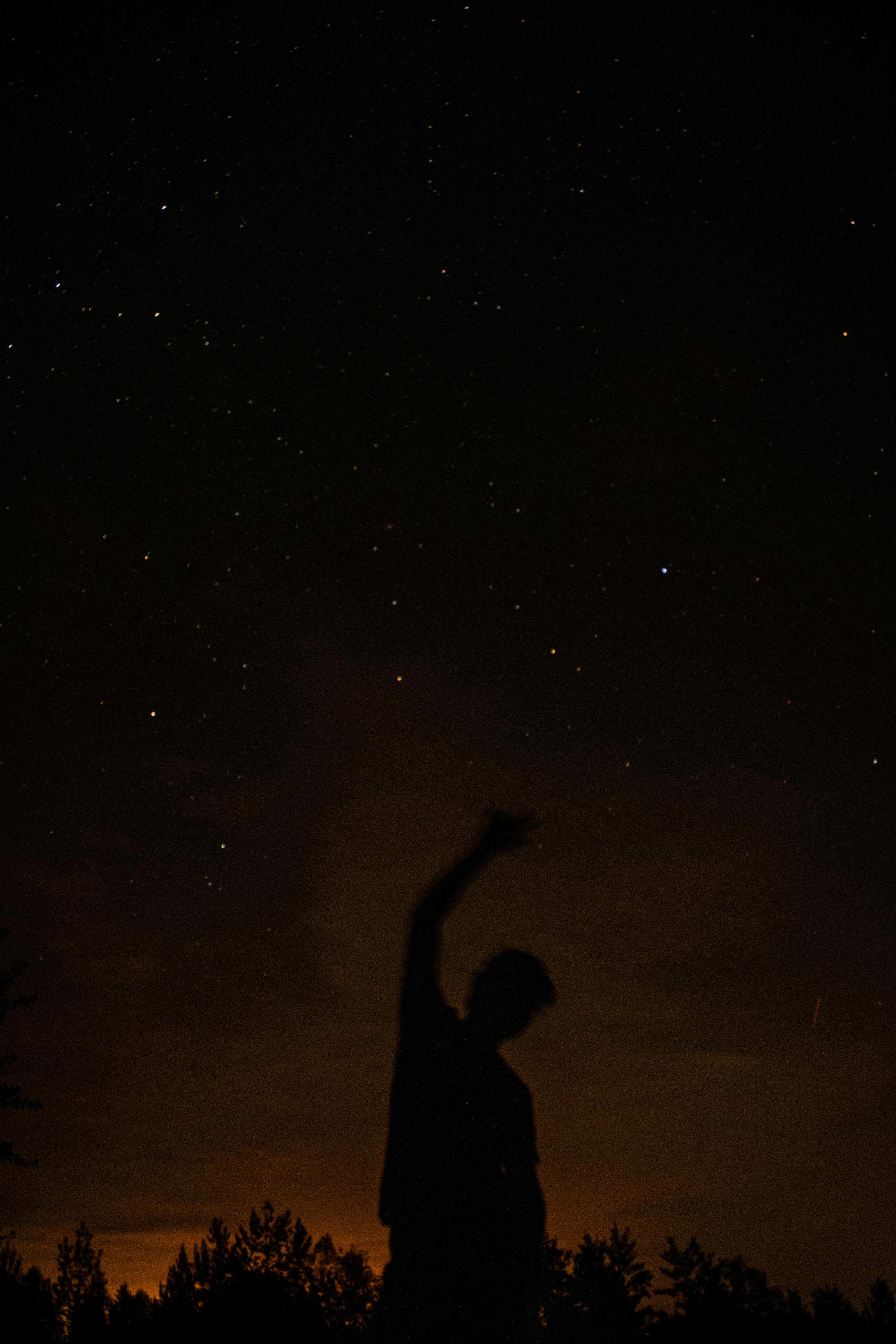 silhouette of a person reaching for the stars