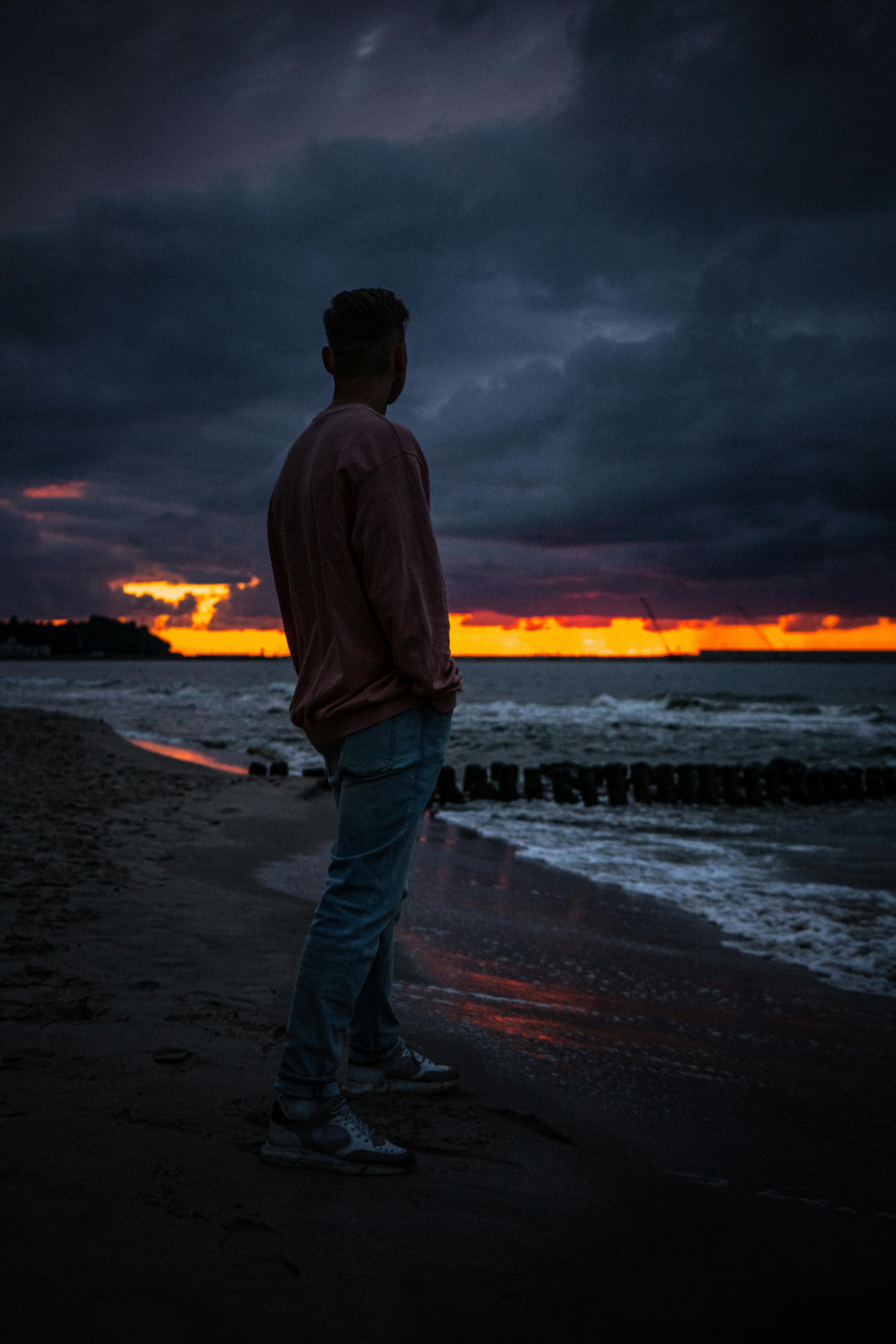 A Man Sitting on the Seawall at Night · Free Stock Photo