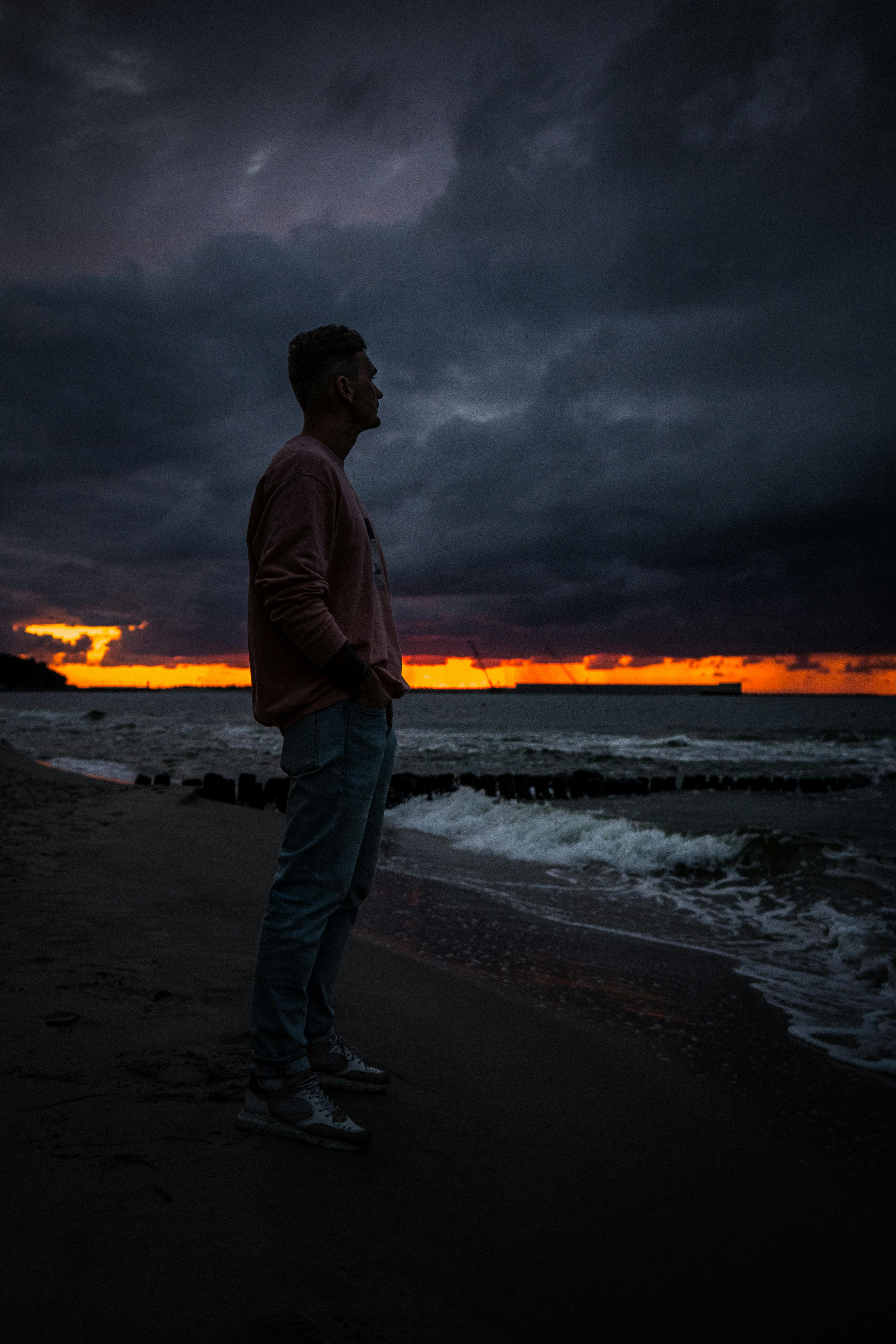 A Man Sitting on the Seawall at Night · Free Stock Photo