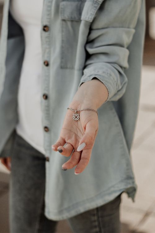 Free Close-up of a woman wearing denim, showcasing a silver pendant in an outdoor setting. Stock Photo