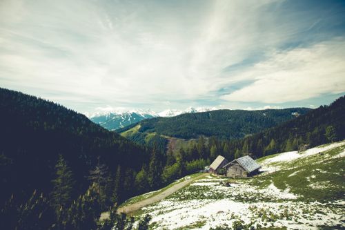 Free A scenic view of rustic cottages nestled in a snowy mountain landscape with vast skies and hills. Stock Photo