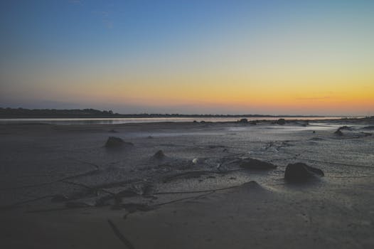 Calm and scenic evening seascape at Bharuch beach during sunset with rocks and sand.