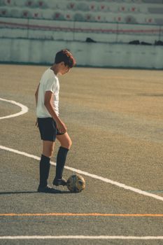 Teen boy practicing soccer on field during day, embodying focus and determination.