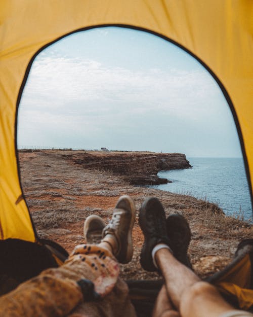 Person in Black Pants and Brown Shoes Sitting Inside Tent