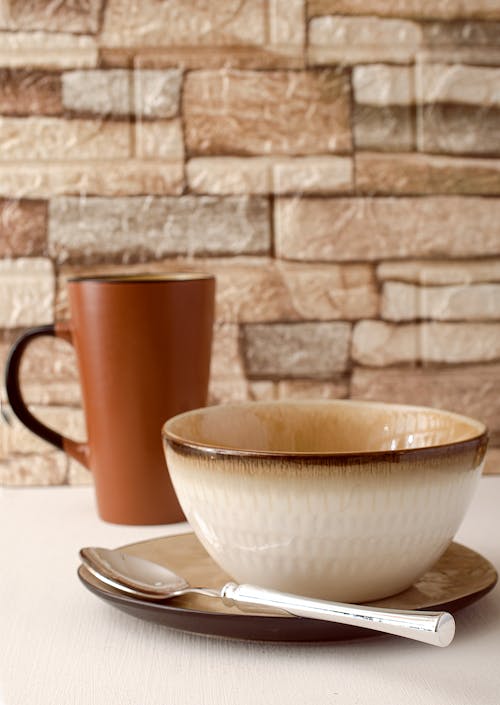 Free Ceramic Bowl on Saucer Beside Silver Spoon and Ceramic Cup Stock Photo