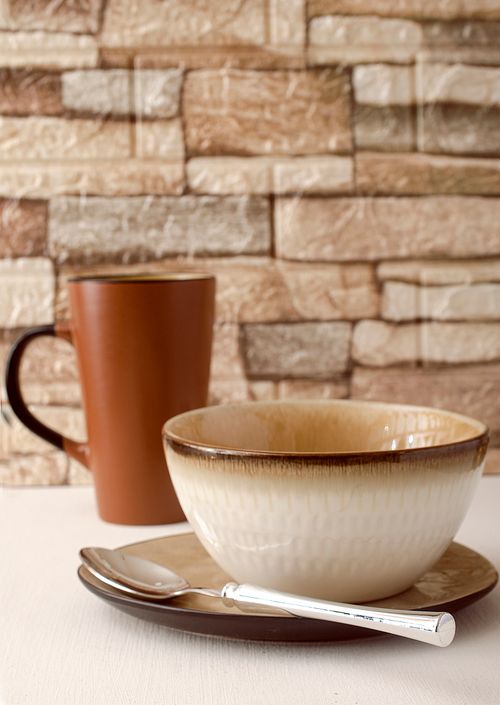Free A cozy close-up of ceramic bowl and mug set against a rustic brick background. Ideal for kitchen interiors. Stock Photo