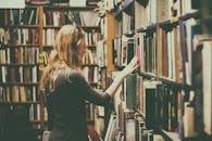 Woman in Black Long-sleeved Looking for Books in Library
