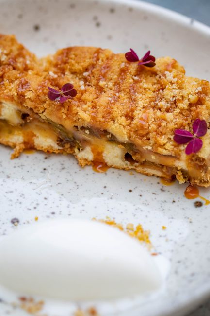 A baking dish of golden apple crisp with a crumbly oat topping, scooped to show the soft cinnamon-spiced apples underneath, served with a scoop of vanilla ice cream.