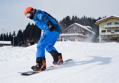 Snowboarder in vibrant gear carving through snowy slopes near a ski resort on a bright winter day.