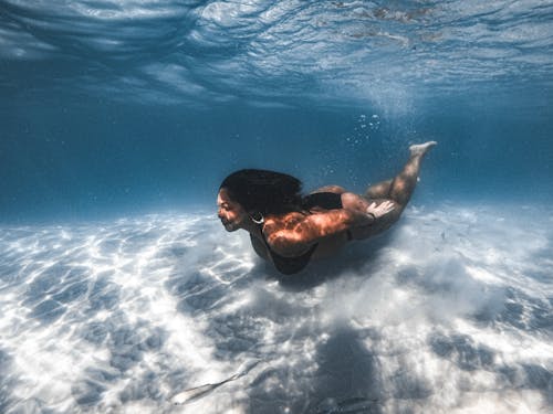 Man in Blue Shorts Swimming in Water