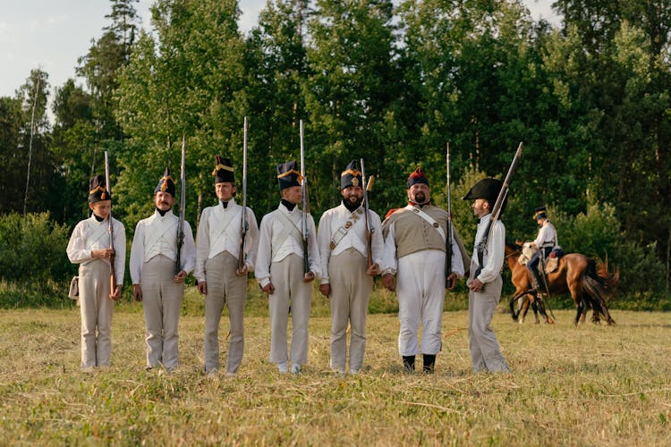 Group Of Soldiers Standing On Grass Field