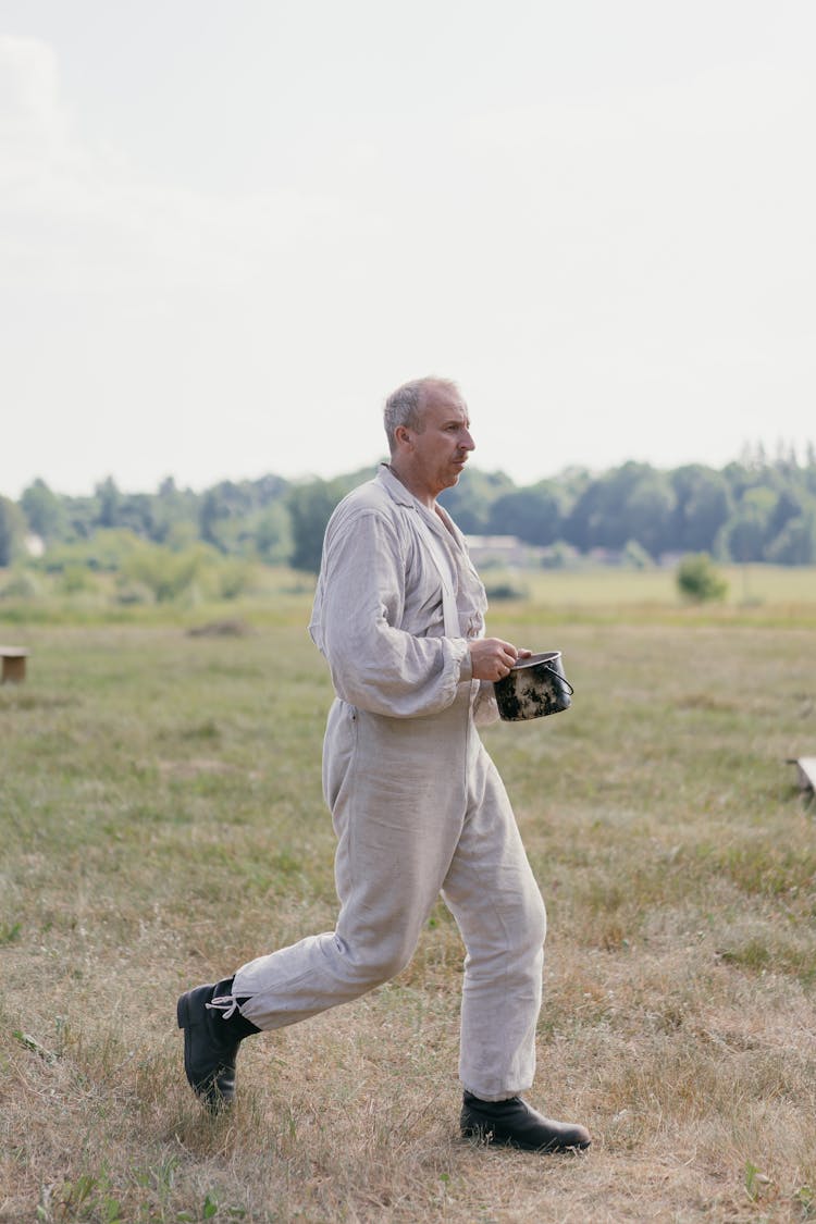 Man In White Clothing Walking On Grass Field