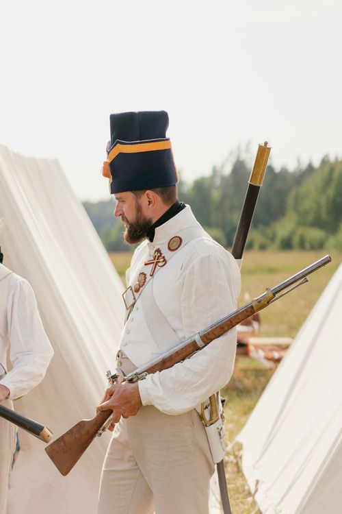 Free A historical reenactment with a soldier in vintage uniform holding a rifle outdoors. Stock Photo