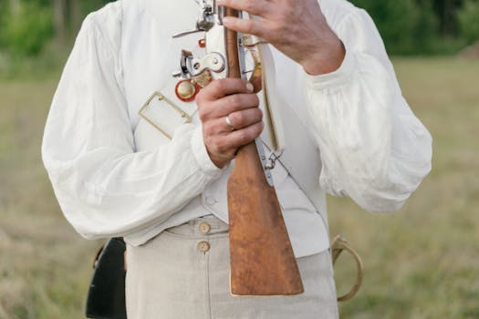 A soldier in traditional attire holds a vintage rifle in an outdoor setting, emphasizing history and military heritage.