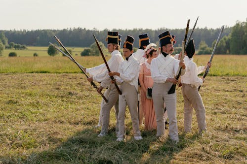 Men in Vintage Uniforms Surrounding a Woman during Historical Reenactment