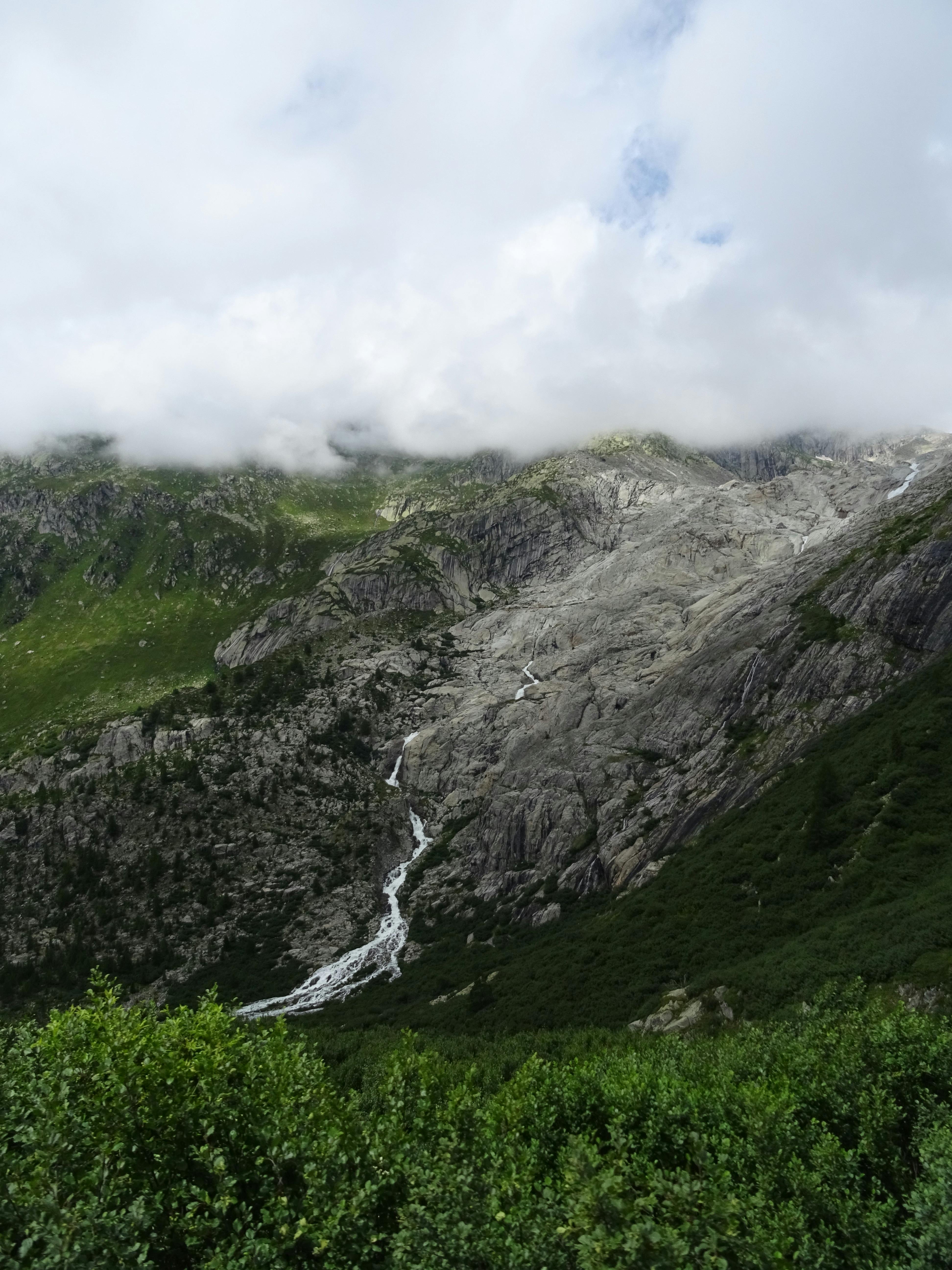 Majestic alpine view in Obergoms, Switzerland, with rocky mountains and lush greenery.