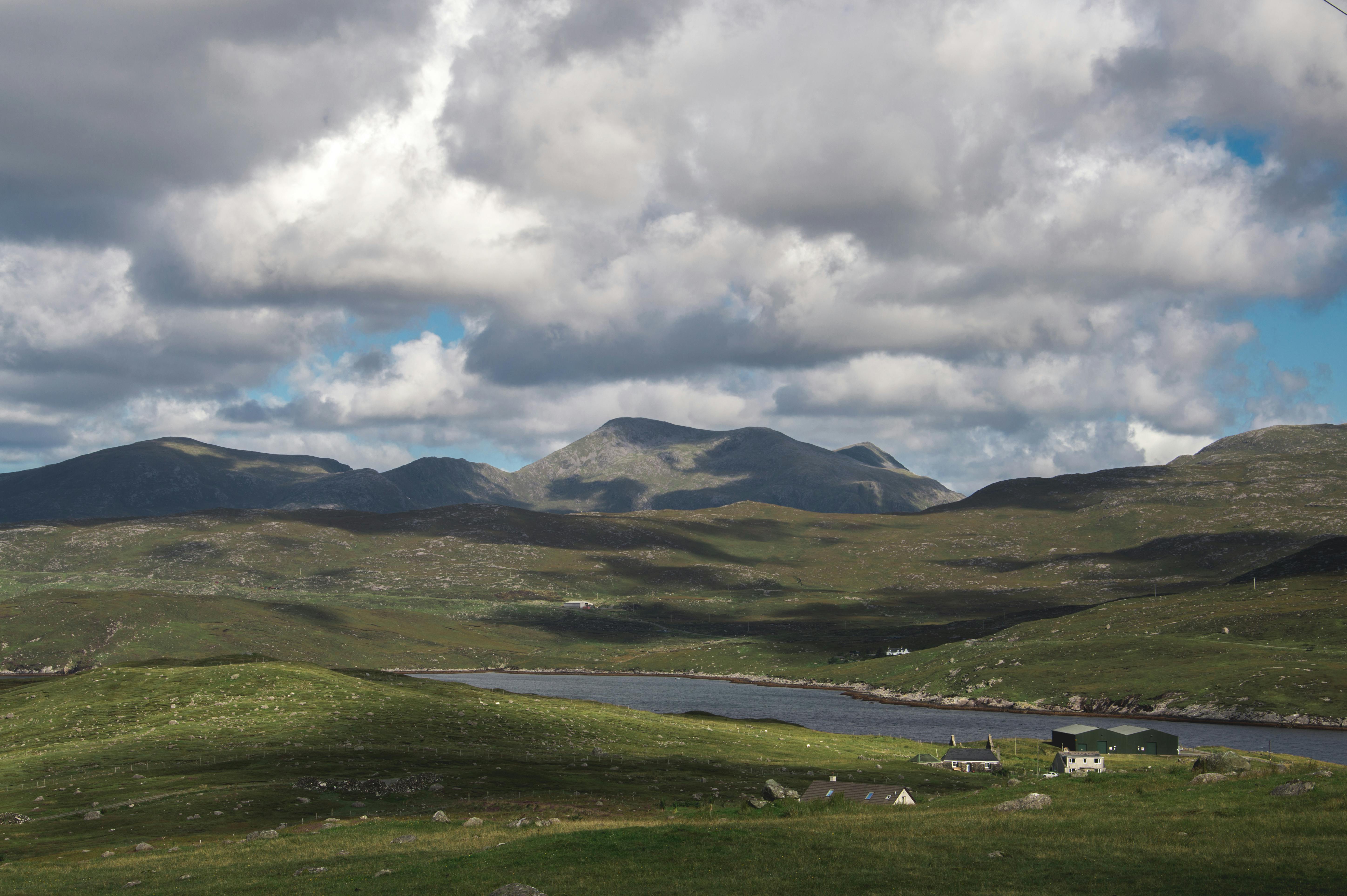 Picturesque landscape of Scottish Highlands featuring green hills and a vibrant blue sky with clouds.