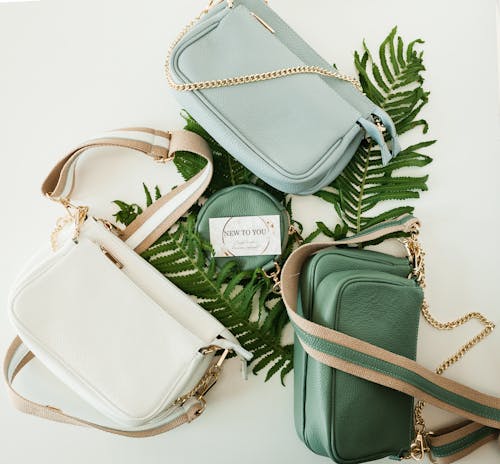 Free Green, Gray and White Leather Handbags on Fern Leaves Stock Photo