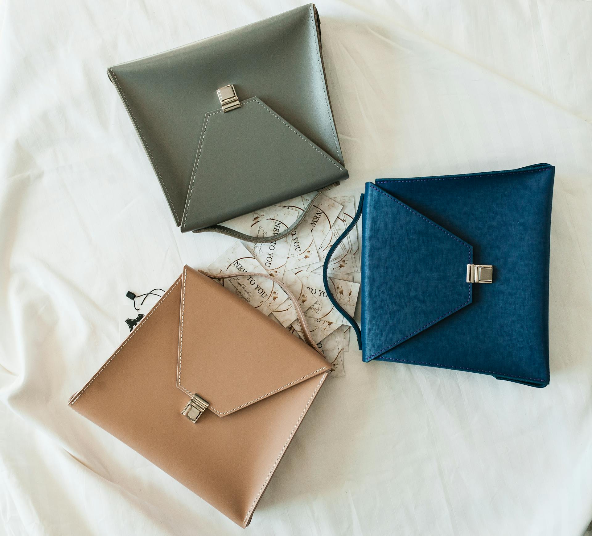 Three stylish leather handbags on a designer background.