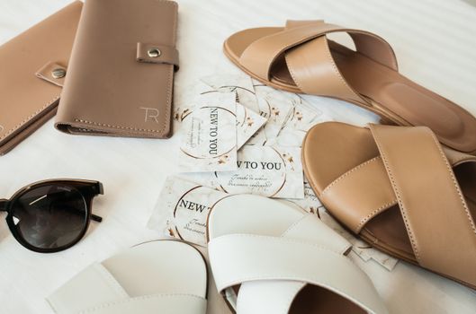 A chic flat lay of summer accessories including sandals, wallets, and sunglasses.