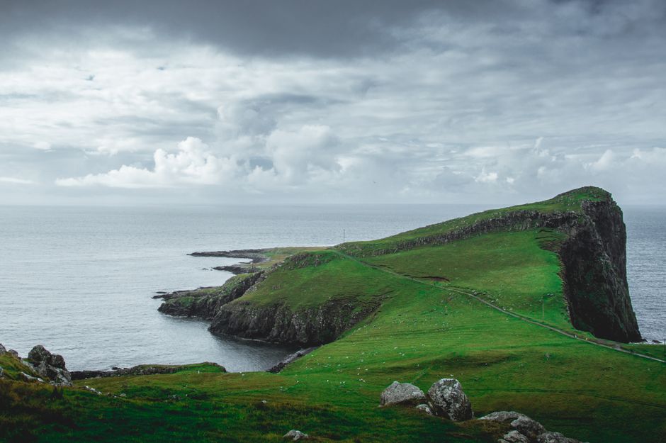 A breathtaking view of Neist Point with lush green highlands and dramatic cliffs overlooking the ocean.