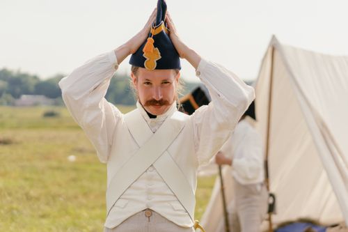 Free A reenactor in vintage military uniform adjusts his hat during an outdoor event. Stock Photo