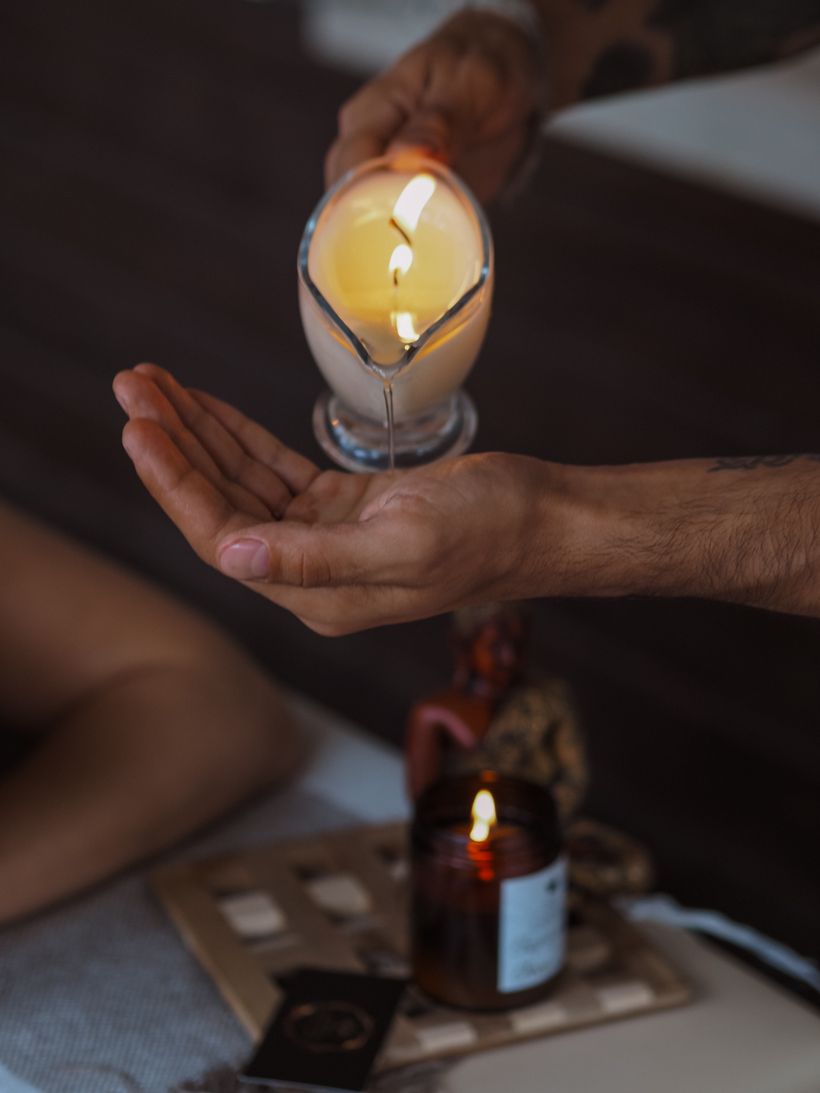 Huile de massage versée dans une ambiance tamisée à la bougie