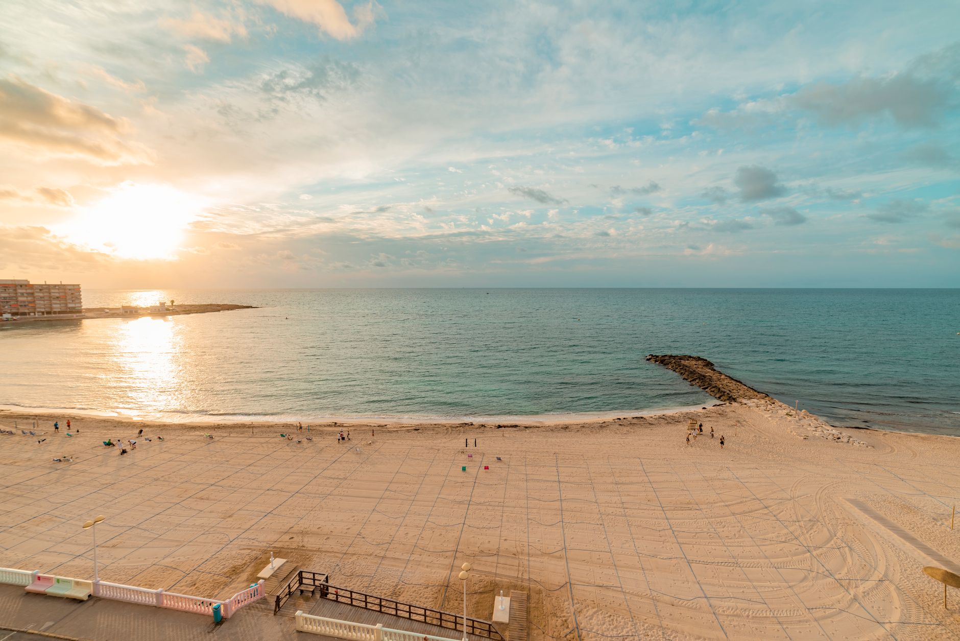 Beautiful sunset over Torrevieja beach with calm waves and golden skies.