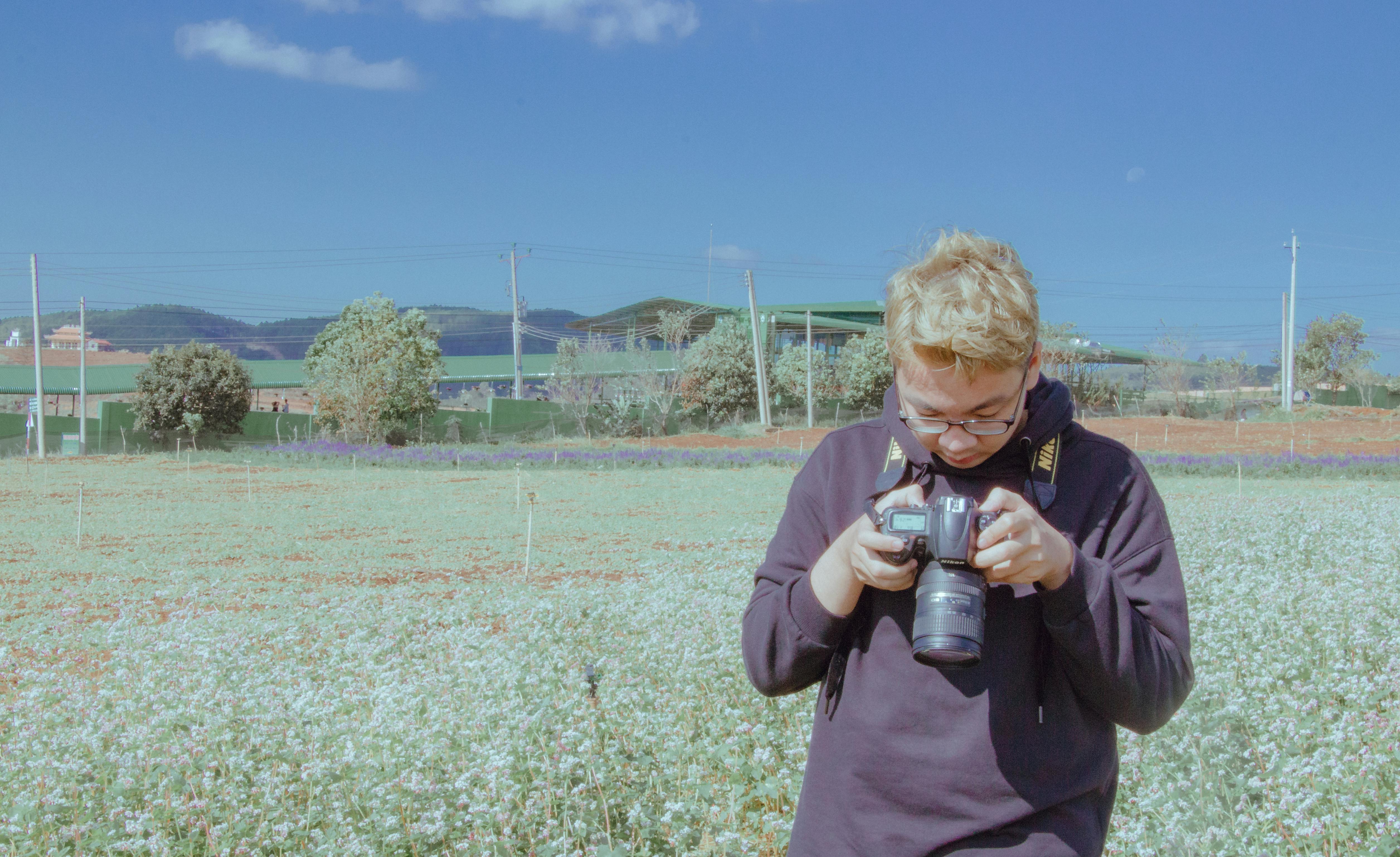 man holding black dslr camera under blue sky