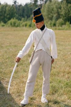 A soldier in historical uniform with saber, outdoors setting.