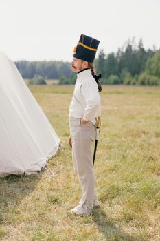 Side view of a soldier in historical uniform on a grassy field, perfect for military reenactment themes.