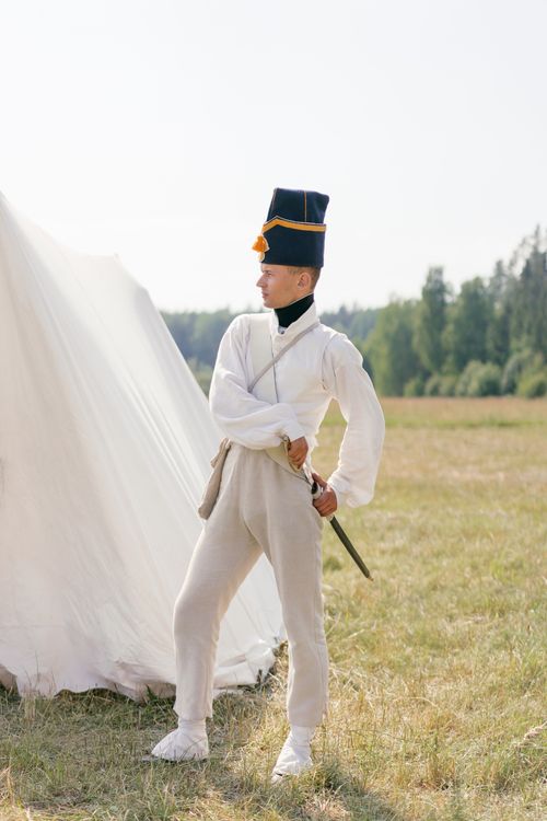 Free Man in historical uniform with saber standing by a tent outdoors. Stock Photo