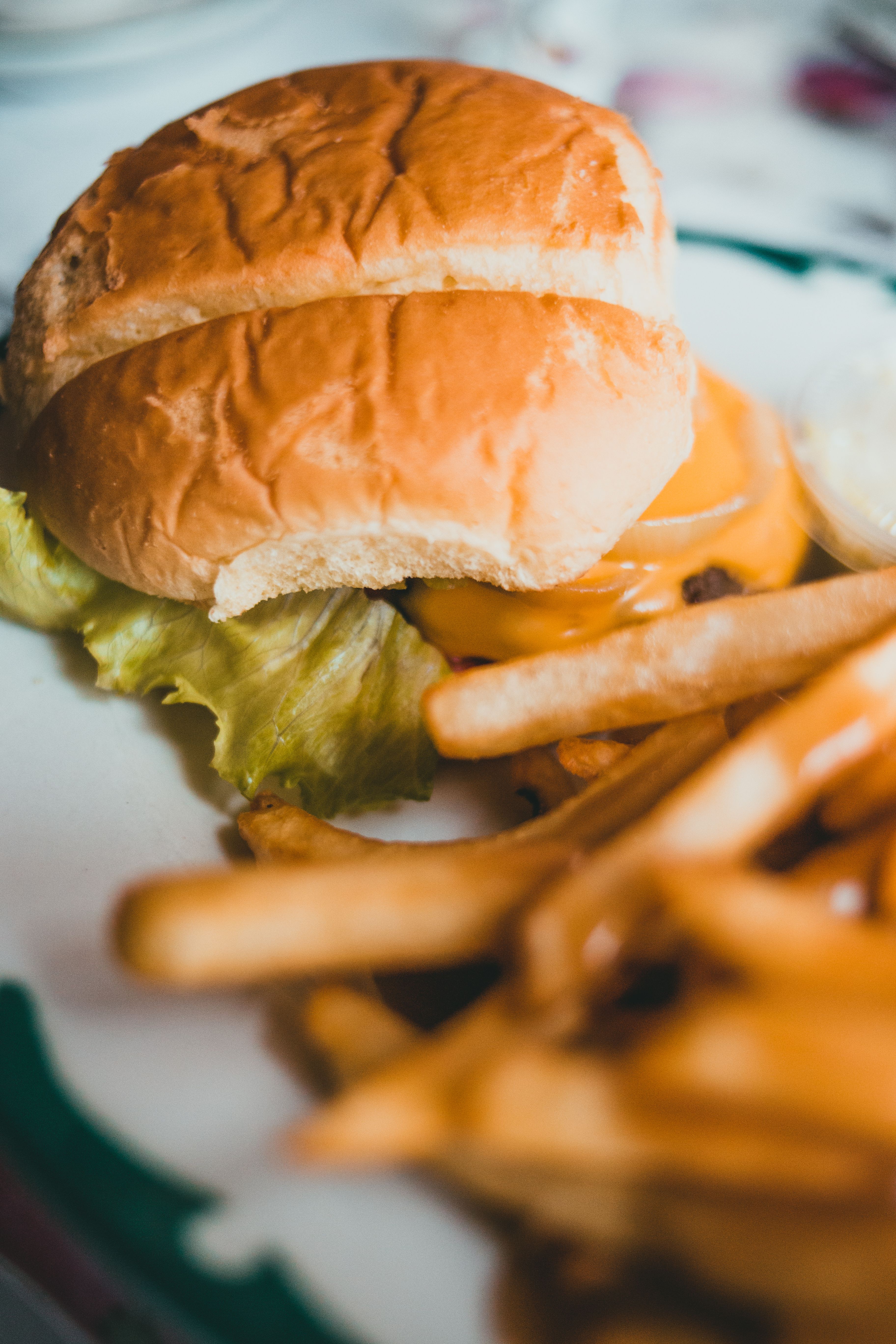 Appetizing close-up of a cheeseburger with lettuce and fries, perfect for food lovers.