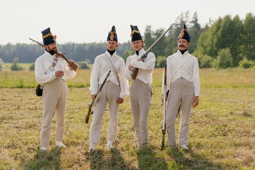 Free Four soldiers in vintage uniforms with rifles in a grassy field. Stock Photo