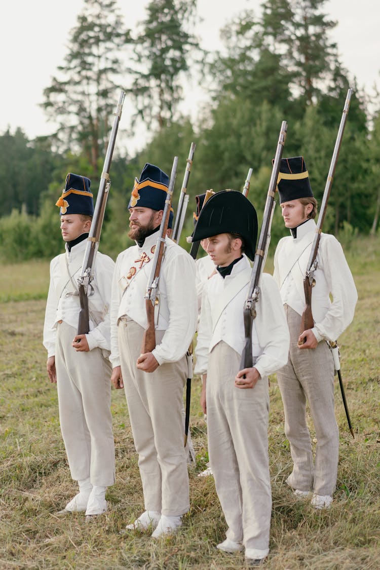 A Group Of Soldiers Holding Rifles While Standing On The Field