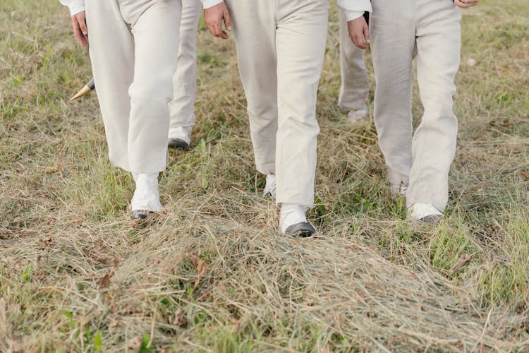 A Group Of People Walking On Grass Field