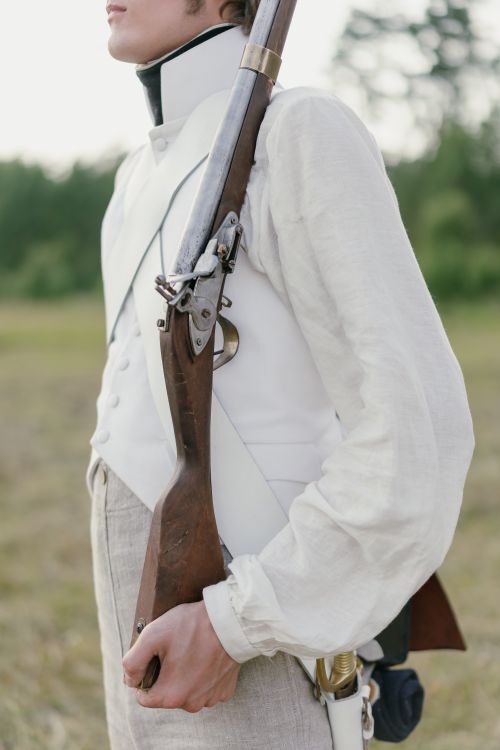 Free A soldier in historical uniform holding a vintage rifle standing in an open field. Stock Photo