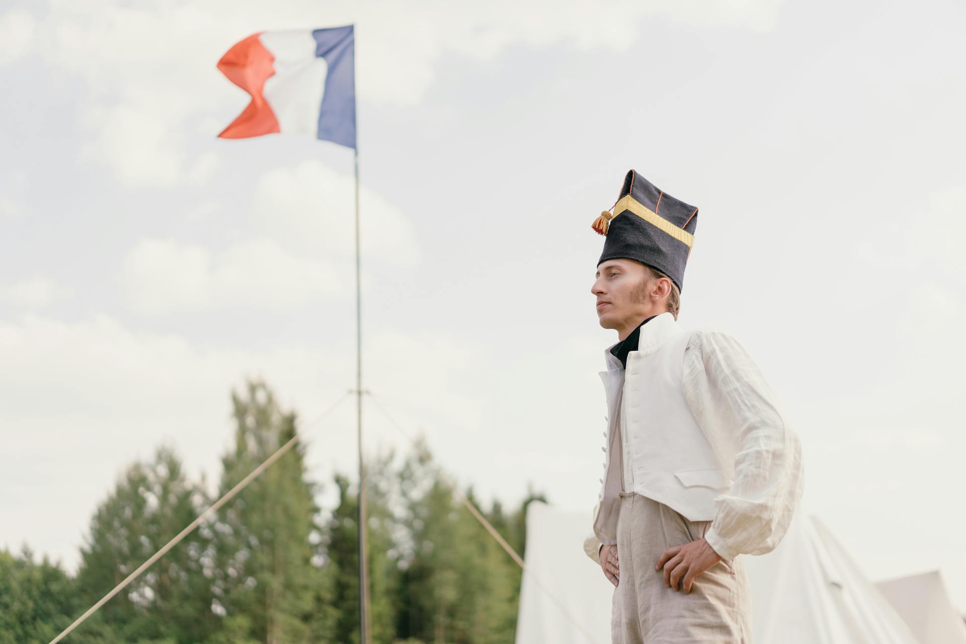 Soldier with Hat Standing by French Flag in Camp