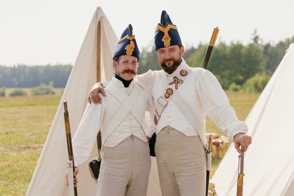 Two soldiers in historical uniforms posing outdoors with rifles at a reenactment event.