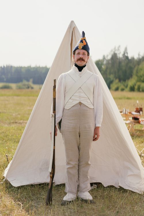 Free A reenactor in historical uniform poses with a musket outdoors. Stock Photo