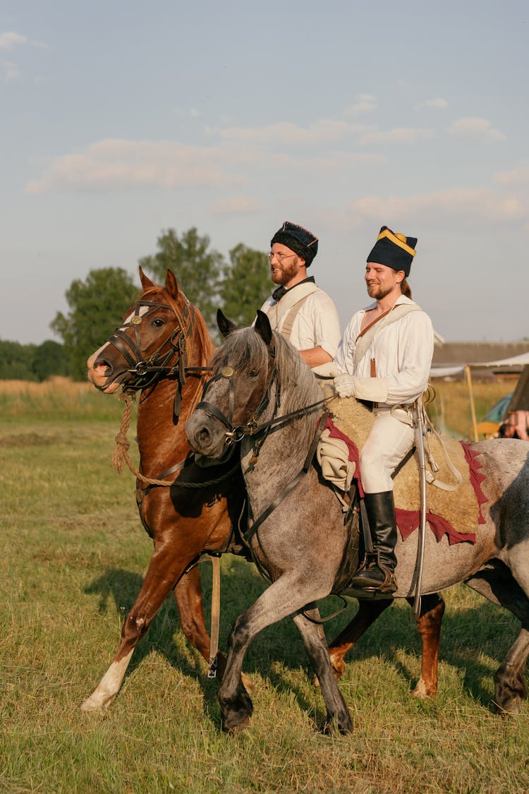 Men Riding Horses On Green Grass Field