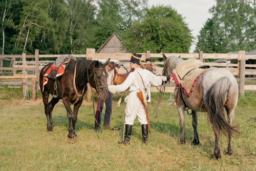 Soldiers in Historical Uniforms Taking Care of Horses 