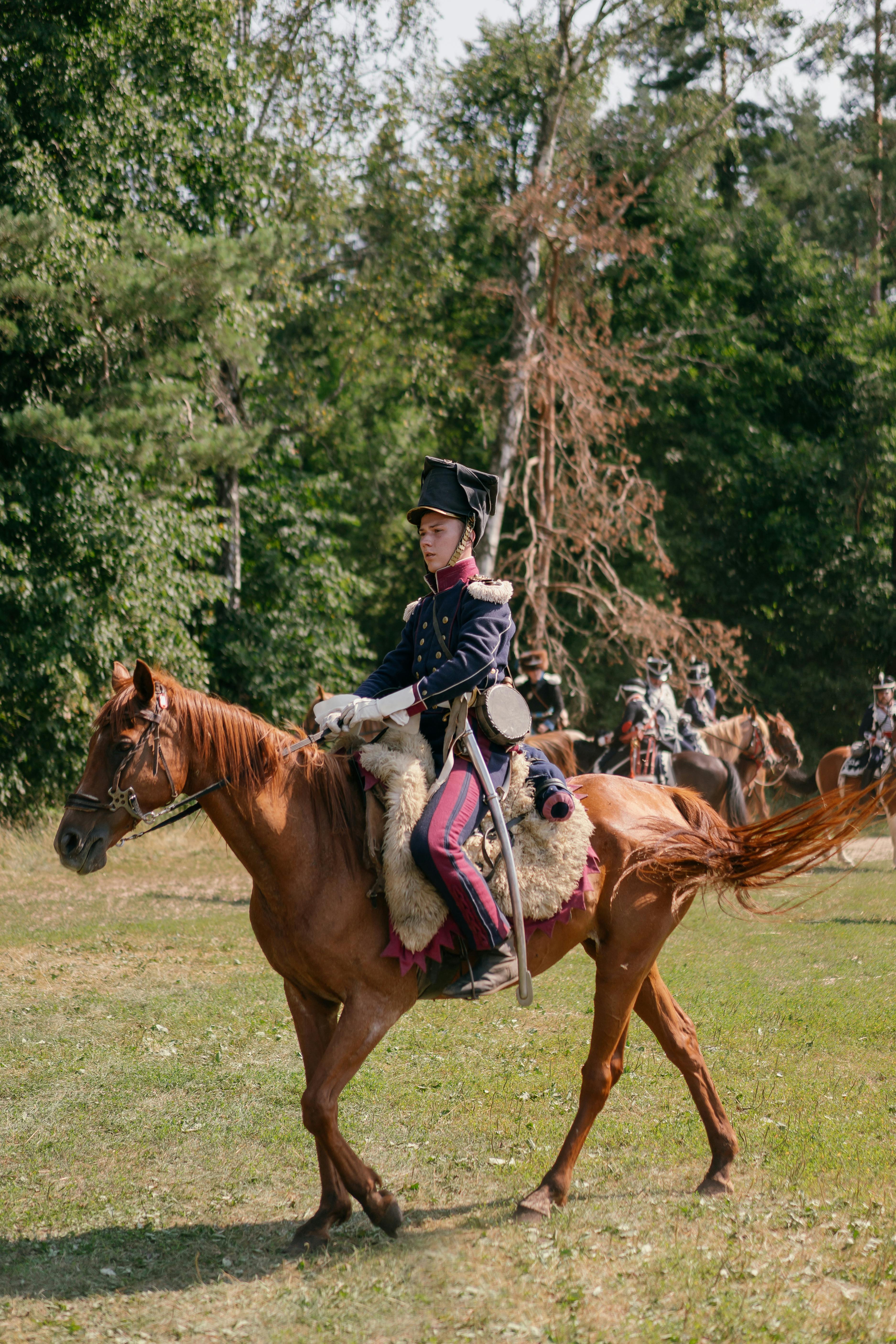 Man in historical military uniform on horseback during reenactment event.