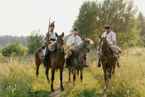 Soldiers in Historical Uniforms Riding Horses on the Country Road 