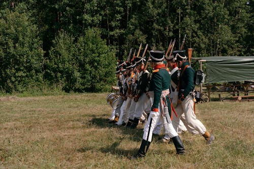 Soldiers with Rifles Wearing Historical Uniforms Marching in the Grass Field 