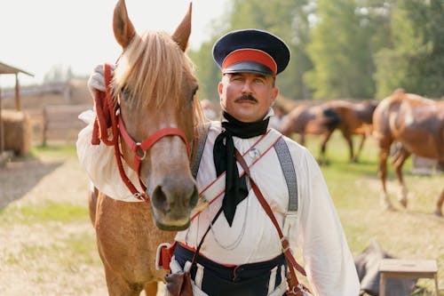 Man in Military Uniform Standing Beside a Horse