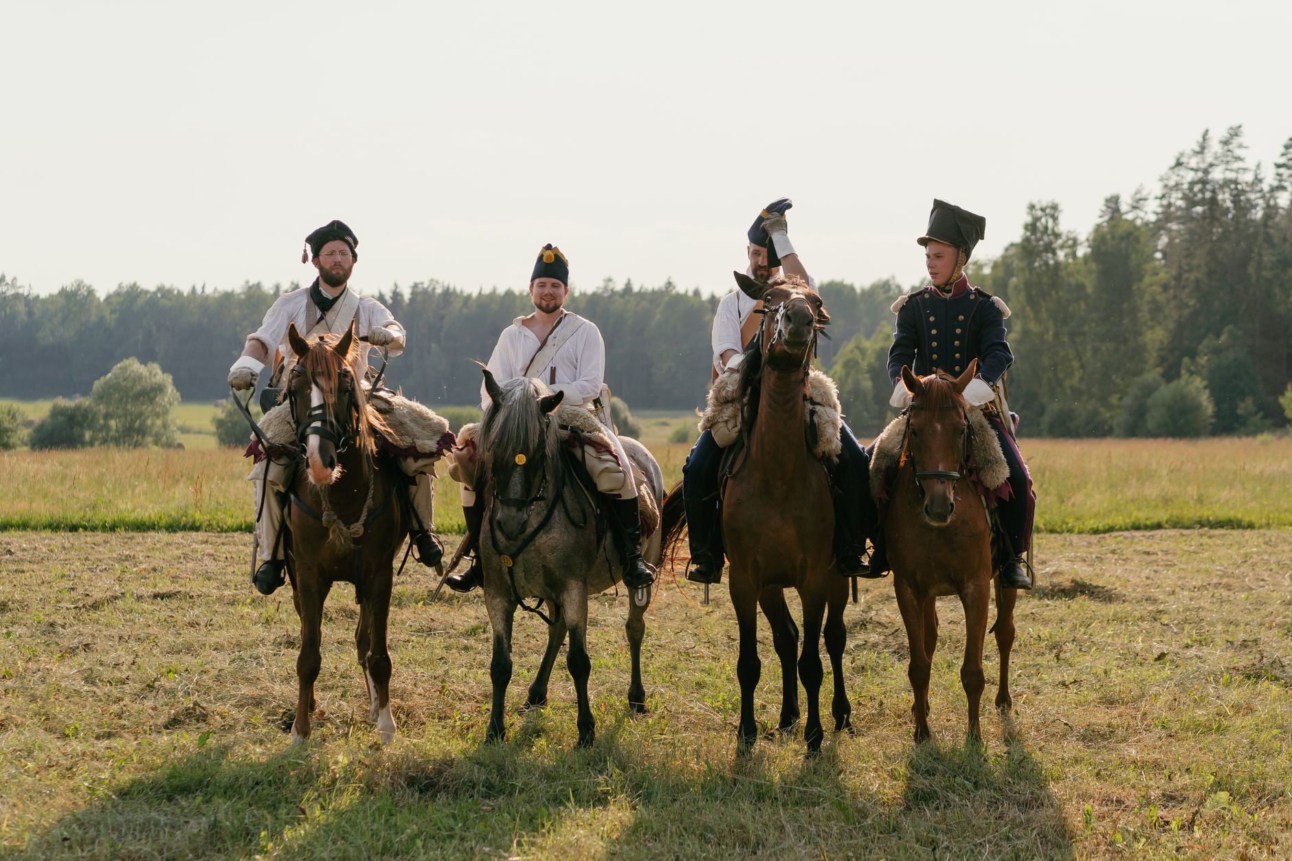 Four soldiers on horseback in vintage uniforms, reenacting historical cavalry scene.